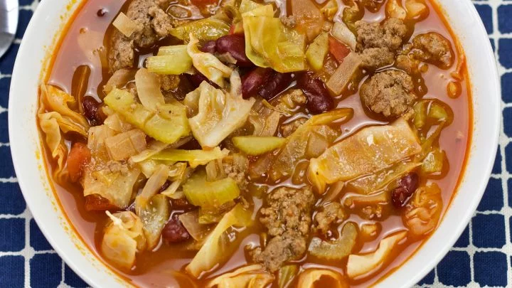 Cabbage Soup In A White Bowl On A Blue Plaid Cloth