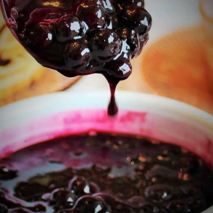 Blueberry sauce dripping off a spoon