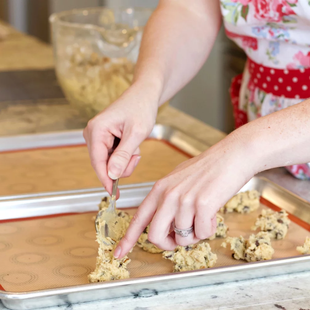 Creamy Chocolate Cookie Dough Being Dropped By Teaspoonfuls Onto The Cookie Sheet Covered In A Silicone Mat.