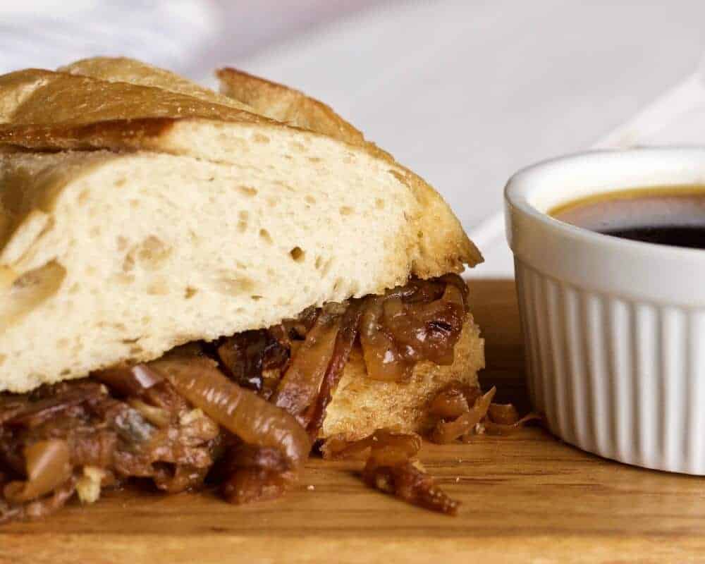 The Crock Pot French Dip Sandwich With Caramelized Onions Dipped And Ready To Eat