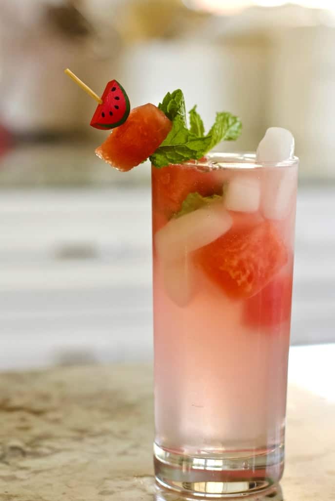 Watermelon Peach Cocktail Garnished With Watermelon Chunks, Mint Leaves And A Cute Bamboo Cocktail Stick