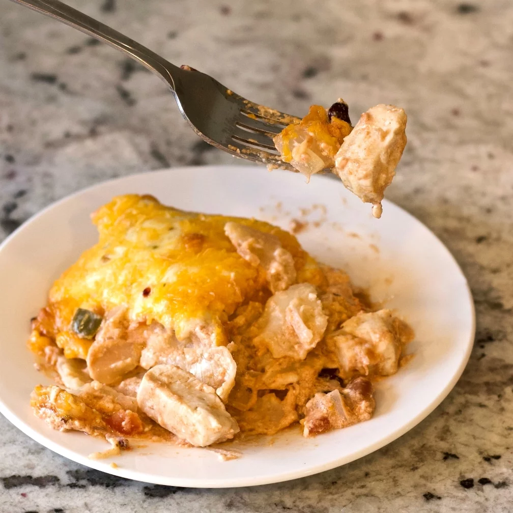 Chili Chicken Casserole On A White Plate With A Fork Full Above It.