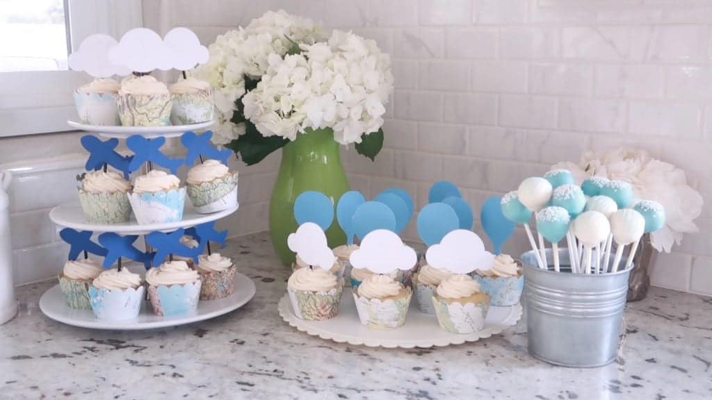 Baby Shower Cupcakes pe platouri cu hortensii albe și o cutie de cake pops