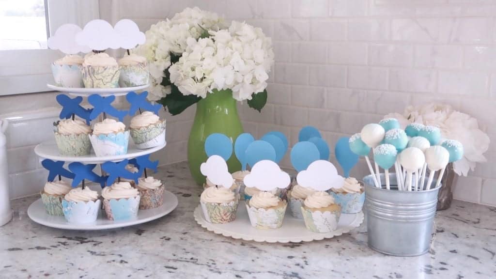 Cupcakes para baby shower en bandejas con hortensias blancas y una lata de cake pops