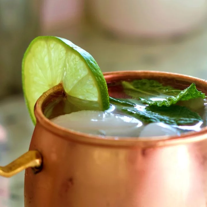 Moscow mule vodka drink in a copper mug with lime and mint leaves.