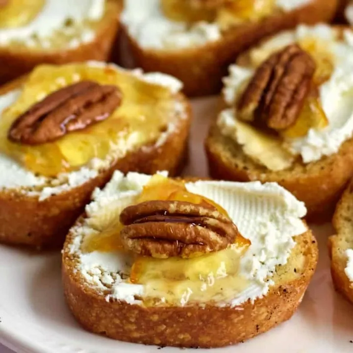 Goat cheese crostinis with marmalade on a party tray.