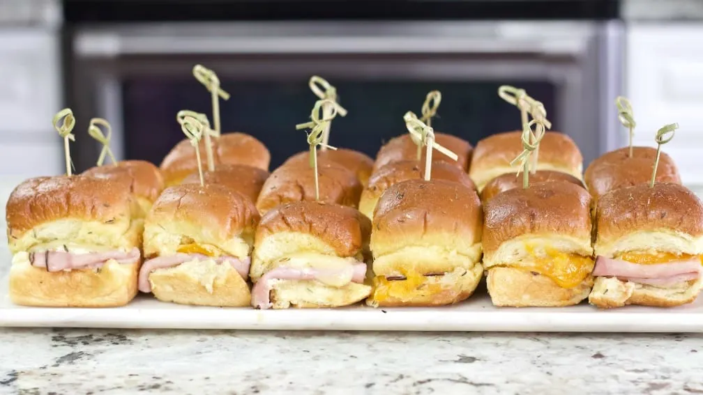 Hawaiian Roll Ham And Cheese Sliders Recipe 2 Side Shot Of Ham And Cheese Sliders With Bamboo Picks And On A Party Tray.