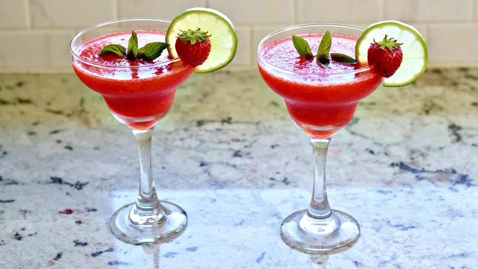 Frozen Strawberry Daiquiris Sitting On A Counter Fully Garnished.