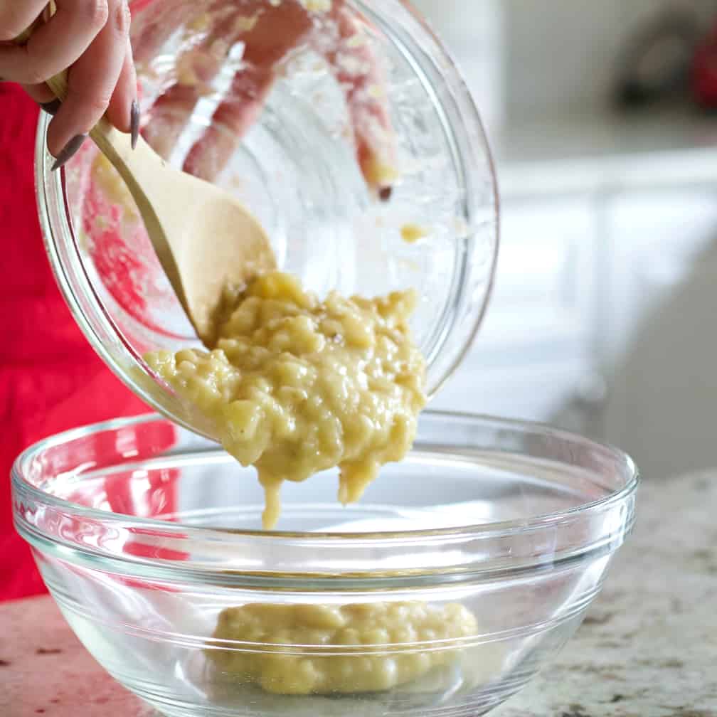 Pouring The Mashed Bananas Into A Large Mixing Bowl.