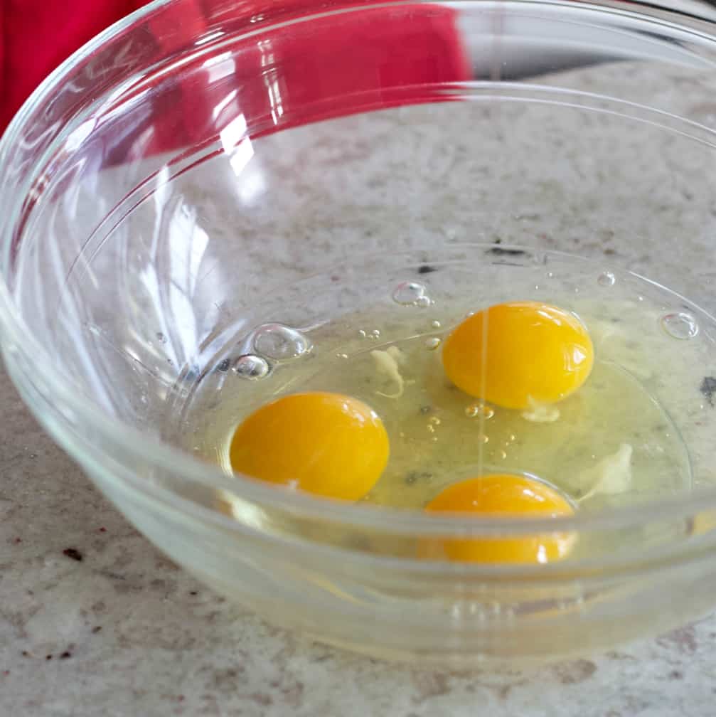 Three Eggs Cracked Into A Glass Mixing Bowl