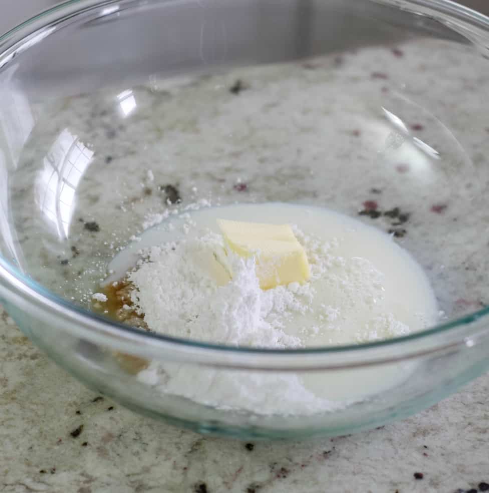 Milk, Powdered Sugar And Vanilla With Lemon Juice In A Clear Mixing Bowl.