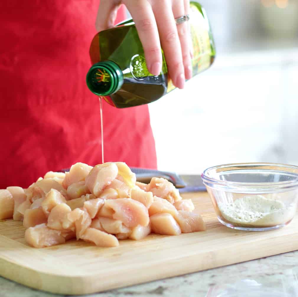 Pouring Oil Over Chopped Chicken On Wooden Board
