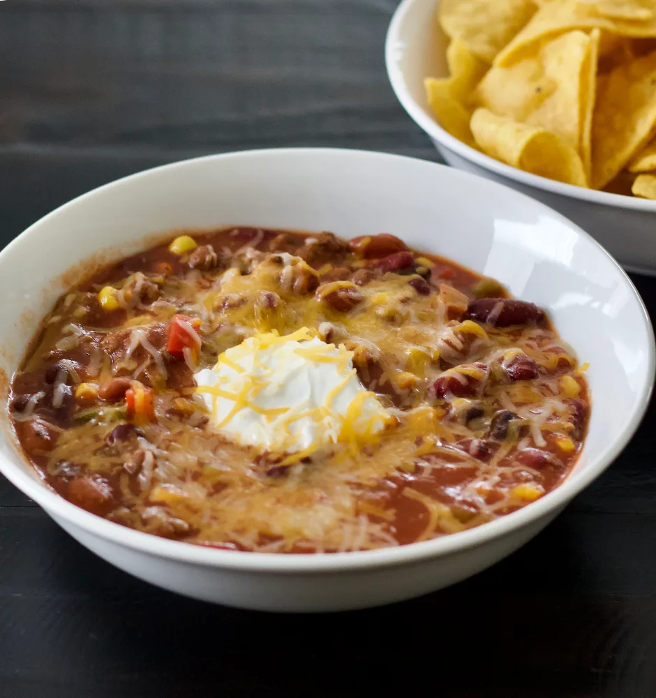Chili With Sour Cream And Cheddar Cheese On Top. Served With Tortilla Chips