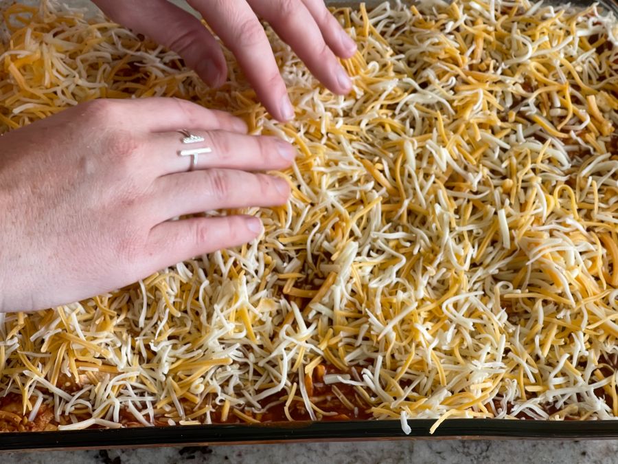 Evenly Layering Cheese As Topp Layer-Chicken Enchilada Casserole