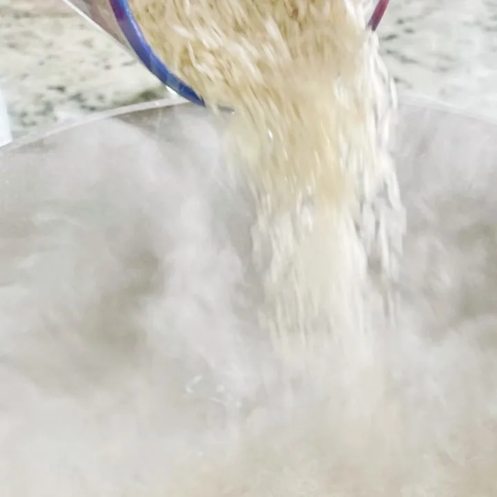 adding rice to boiling water