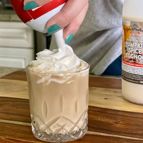 Laying Whipped Cream On Eggnog Cocktail