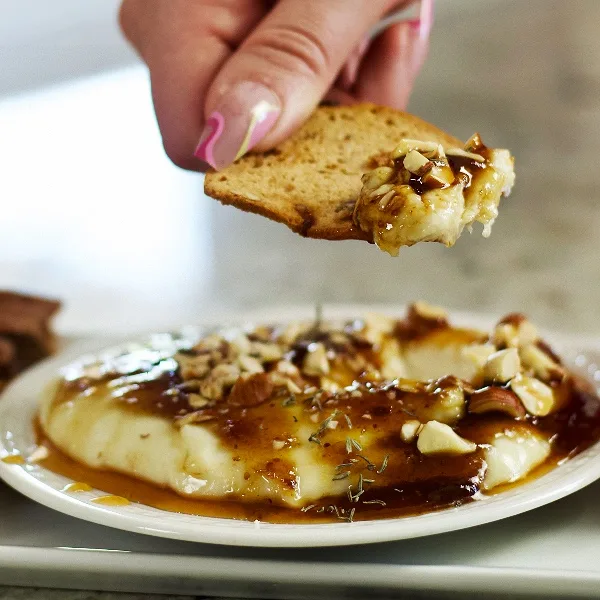 dipping a cracker into whipped brie on a plate