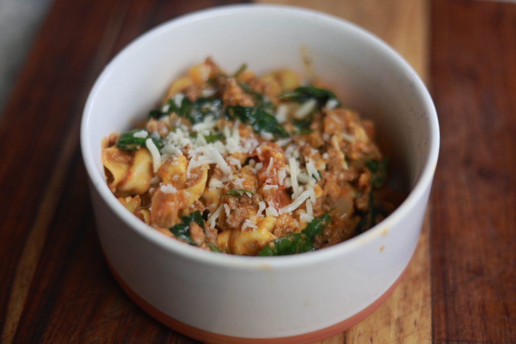 A Bowl Of Pasta With Cheese And Meat