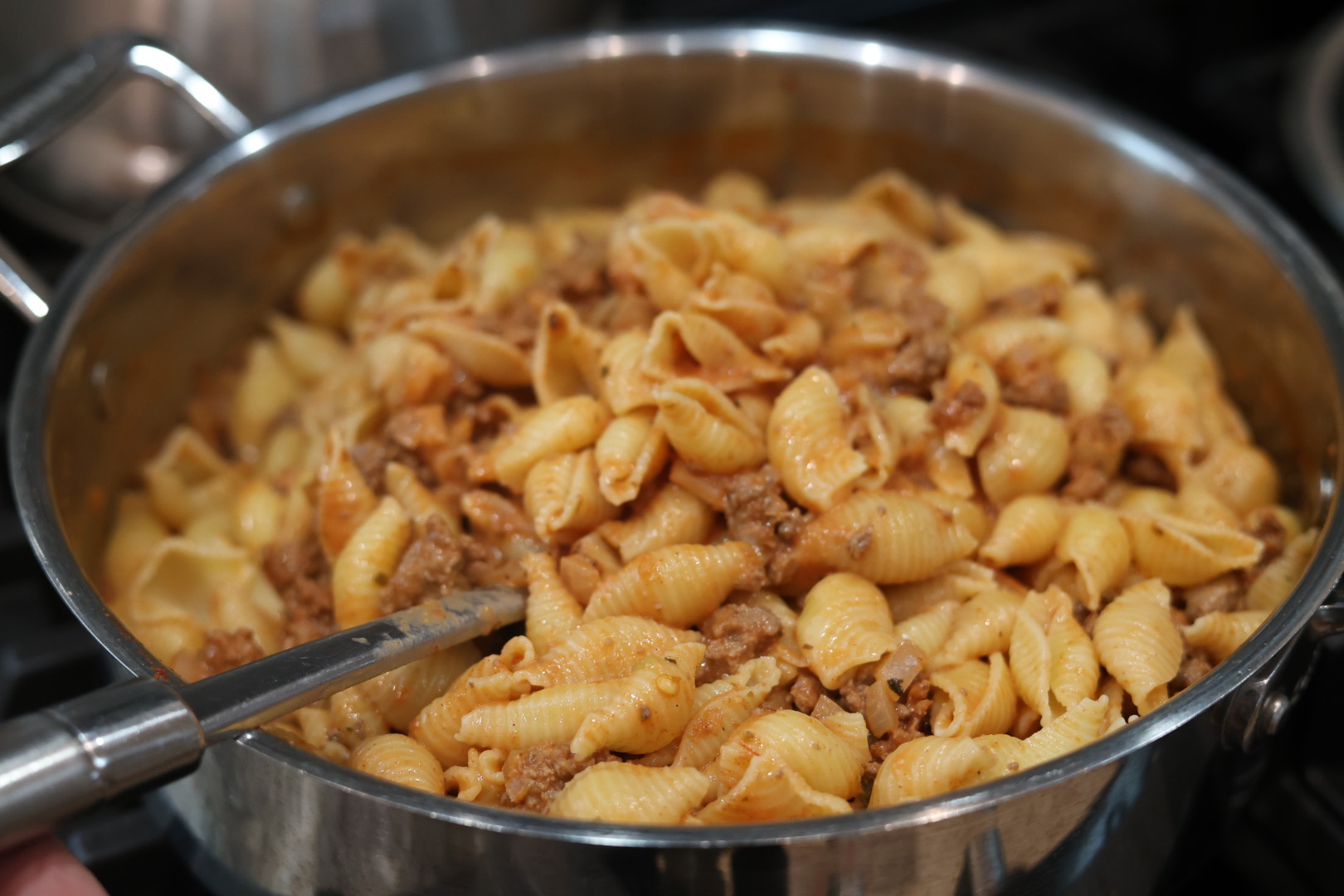 Ultimate Cheesy Beef and Shells Dinner 9 stirring cooked shell pasta into sauce for creamy beef and shells