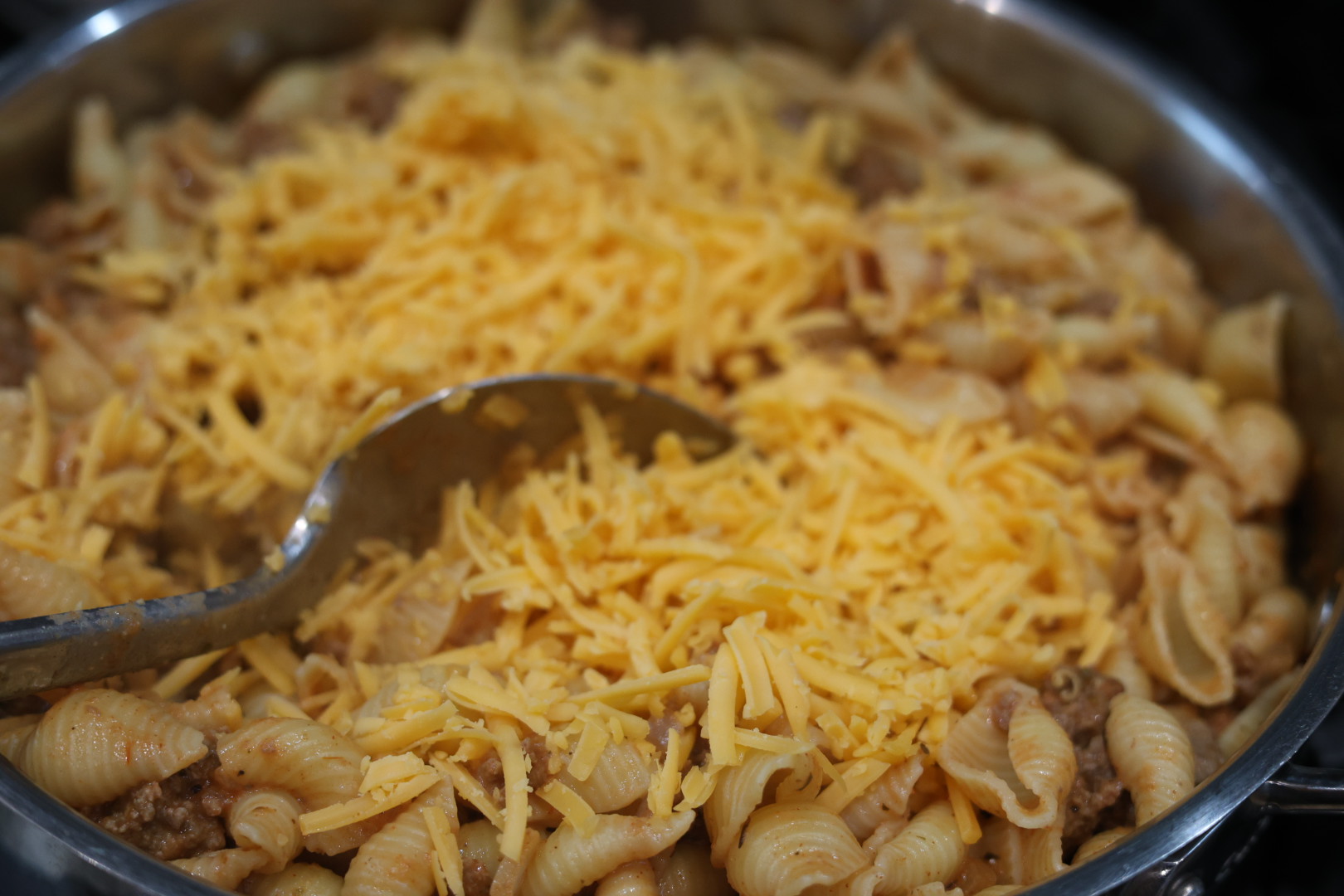 Ultimate Cheesy Beef and Shells Dinner 10 stirring grated cheese into cheesy beef and shells dinner