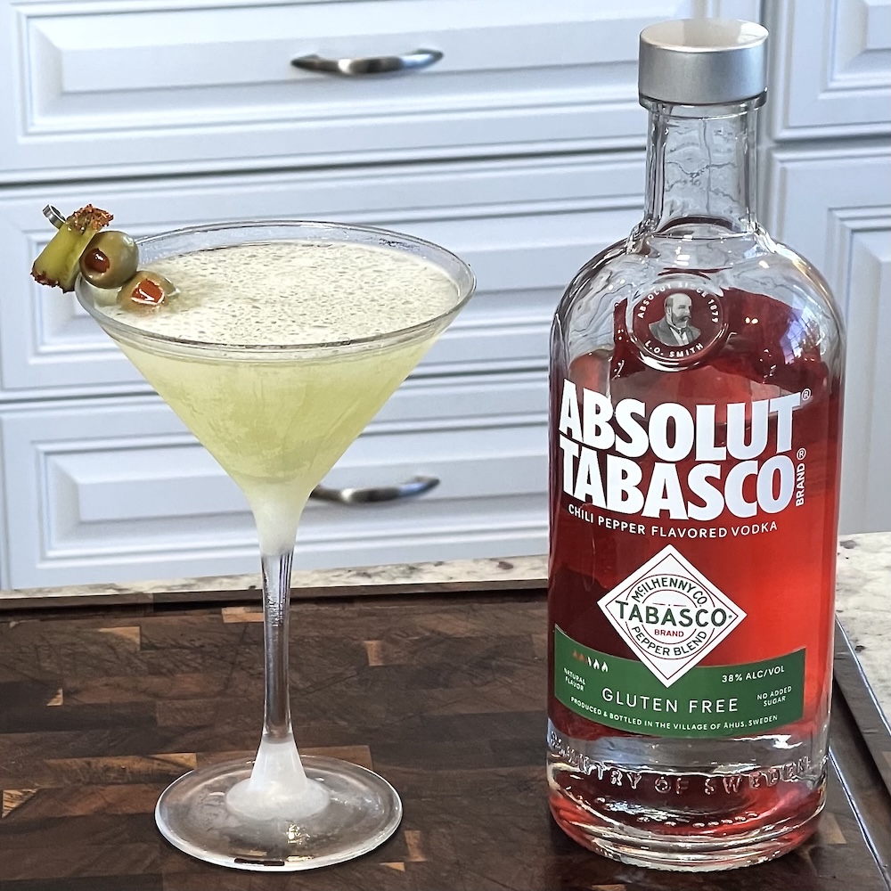 Absolut Tabasco Vodka Martini (Spicy Pickle Martini Recipe) 3 absolut tabasco vodka martini with a bottle of absolut tabasco vodka on a dark board. white kitchen background