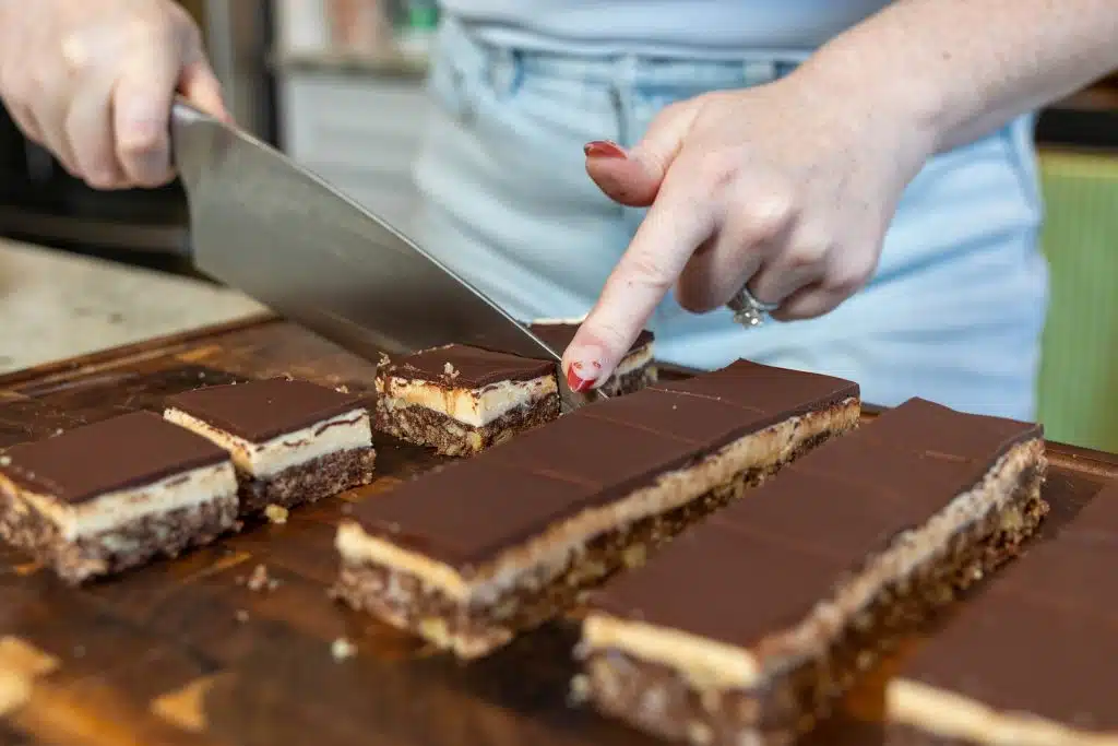 Slicing through Nanaimo Bars and preparing to serve them